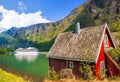 Red cottage against cruise ship in fjord, Flam, Norway