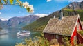 Red cottage against cruise ship in fjord, Flam, Norway