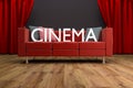 Red couch in front of large cinema curtain
