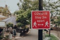 Red Covid-19 Stay 2 Metres Apart sign on a sidewalk in Bourton-on-Water, Cotswolds, UK