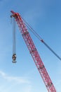 Red crane boom with hook against blu sky