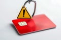 A red credit card with an embedded chip, with a yellow caution triangle and exclamation point, highlighting a fraud alert warning Royalty Free Stock Photo