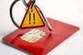 A red credit card with an embedded chip, with a yellow caution triangle and exclamation point, highlighting a fraud alert warning Royalty Free Stock Photo