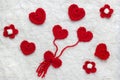 Red crochet wool hearts, flowers and ribbon on white fur background. The concept for 14 February, romantic Valentine day, love