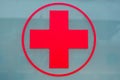Red cross sign on a grey glass background. Symbol of medicine and healthcare on a window. Royalty Free Stock Photo