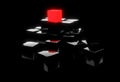 Red cube on top of heap of black cubes over black background - software module, teamwork or standing out from the crowd leadership