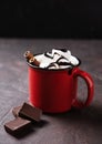 Red cup of aroma hot chocolate with marshmallows and cinnamon on a brown background. Concept cozy drink. Front view and copy