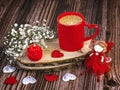 A red cup of coffee with a heart, a fairy doll, a candle in the shape of a rose, gypsophila flowers