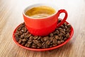 Red cup with espresso on saucer with coffee beans on table Royalty Free Stock Photo