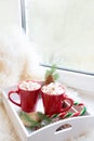 Red cup of hot chocolate with marshmallow on windowsill. Weekend concept. Home style. Christmas morning. Royalty Free Stock Photo