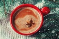 Red cup of hot cocoa or hot chocolate on knitted background with fir tree, traditional beverage for winter time