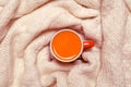 Red cup of hot sea buckthorn tea on backdrop from white knitted sweater on a rustic wooden background. Immunization concept. Top Royalty Free Stock Photo