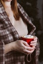A red cup with hot winter drink in the hands of a woman in a warm blanket. Hot chocolate, cocoa, coffee with marshmallows Royalty Free Stock Photo
