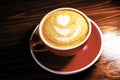 Red cup of latte coffe with froth art on top, half in dark above view Royalty Free Stock Photo