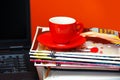 Red cup on magazines and notebook over red