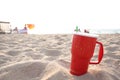 Red cup in sand at sunset. Summer beach party concept with copy space. Royalty Free Stock Photo