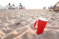 Red cup in sand at sunset. Summer beach party concept with copy space. Royalty Free Stock Photo