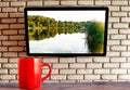 Red cup on the table tv on the wall of decorative brick