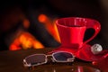 Red cup of tea or coffee and chocolate near fireplace on wooden Royalty Free Stock Photo