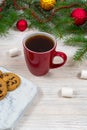 Red cup with tea, coffee with cookies and marshmallows on a white wooden table against the background of a New Year tree Royalty Free Stock Photo