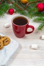 Red cup with tea, coffee with cookies and marshmallows on a white wooden table against the background of a New Year tree Royalty Free Stock Photo