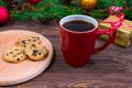 Red cup with tea, coffee with cookies and marshmallows on a wooden table against the background of a New Year tree with Royalty Free Stock Photo