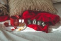 Red cup of tea with kumquat on the plate and two hearts cookies with the word LOVE on a white bed. Valentines day concept.