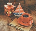 Red cup of tea and letter paper next to vintage decorative boat and lantern on wooden old table. retro filtered image Royalty Free Stock Photo