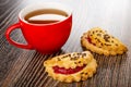 Cup with tea, cookies with raspberry jam and linseeds on wooden table Royalty Free Stock Photo