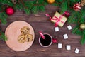 Red cup of tea with white marshmallows with cookies on a wooden table against the background of a Christmas tree with Royalty Free Stock Photo