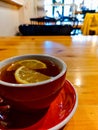 Red cup of warming tea with slice of lemon in small cafe Royalty Free Stock Photo