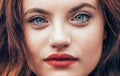 Red curled hair caucasian teen girl with applied red lipstick lips with blue eyes close up fashion portrait. Natural people beauty