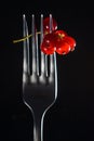 Red currant berries on a fork on a black background