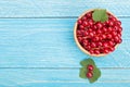 Red currant berries in a wooden bowl with leaf on the blue wooden background with copy space for your text. Top view Royalty Free Stock Photo