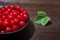 Red currants with leaves in a black bowl on a wooden background. Harvest of ripe summer berries. Closeup Royalty Free Stock Photo