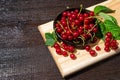 Red currants with leaves in a black bowl on a wooden background. Harvest of ripe summer berries. Closeup Royalty Free Stock Photo