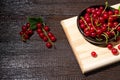 Red currants with leaves in a black bowl on a wooden background. Harvest of ripe summer berries. Closeup Royalty Free Stock Photo