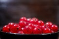 Red currants with leaves in a black bowl on a wooden background. Harvest of ripe summer berries. Closeup Royalty Free Stock Photo