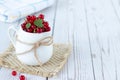 Red currants with leaves in white bowl on rustic wooden table Royalty Free Stock Photo