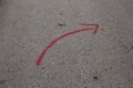 Red curved arrow painted on concrete road with spray paint