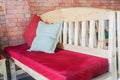 Red cushion on indoors wooden bench for seat with brick wall Royalty Free Stock Photo