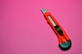 Red cutter knife on red background, sharp knife stationery Royalty Free Stock Photo