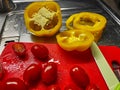 Red cutting board with tomatoes and sweet pepper which are being prepared for a salad Royalty Free Stock Photo