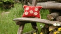 Red daisy cushion on rustic bench, garden background Royalty Free Stock Photo
