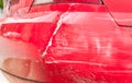 Red damaged car in crash accident with scratched paint and dented rear bumper metal body