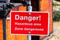 A red danger hazardous area sign in english and french