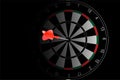 Red dart arrow hit in the target center of dartboard on black background Royalty Free Stock Photo