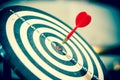 Red dart arrow hitting in the target center of dartboard on bullseye. Royalty Free Stock Photo