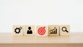 Red dartboard icon on wood cube block and blurred others business icon, set target, research and planning, teamwork, brainstorming