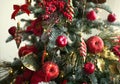 Red decor on a Christmas tree made of apples and poinsettias. Christmas background and frame for new year. Close-up, festive fir t